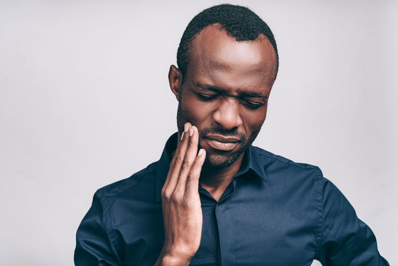 a picture of a person holding his jaw in pain because he needs to treat his internal resorption with a root canal procedure.